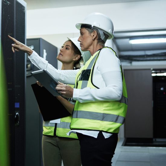 Learning on the job. Cropped shot of two attractive female programmers working in a server room
