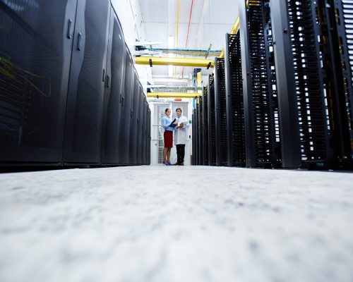 Young mining farm staff standing at the end of long aisle and having talk