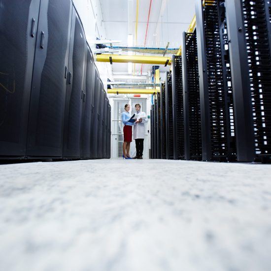 Young mining farm staff standing at the end of long aisle and having talk