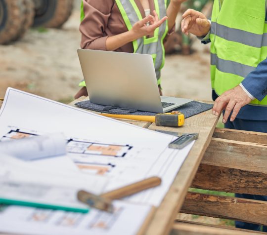 Woman in workwear and her colleague standing outdoors Cropped photo of a young Caucasian female engineer talking to a senior male worker outside